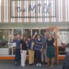 Group of people standing in the open door of The Mill smiling and waving