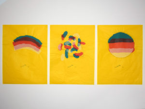 Three prints, with similar themes and colours, but each with a different design inspired by rainbows. They're all on a bright yellow background, with overlapping layers of colours. Underneath each design are the words "With Love From Enfys"